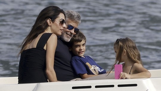 Amal e George Clooney passeiam com filhos de barco por local em que se conheceram 10 anos atrás