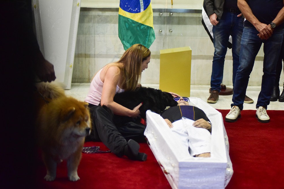 Com caixão no chão, viúva e cachorros de Nahim se despedem do cantor — Foto: Leo Franco/AgNews