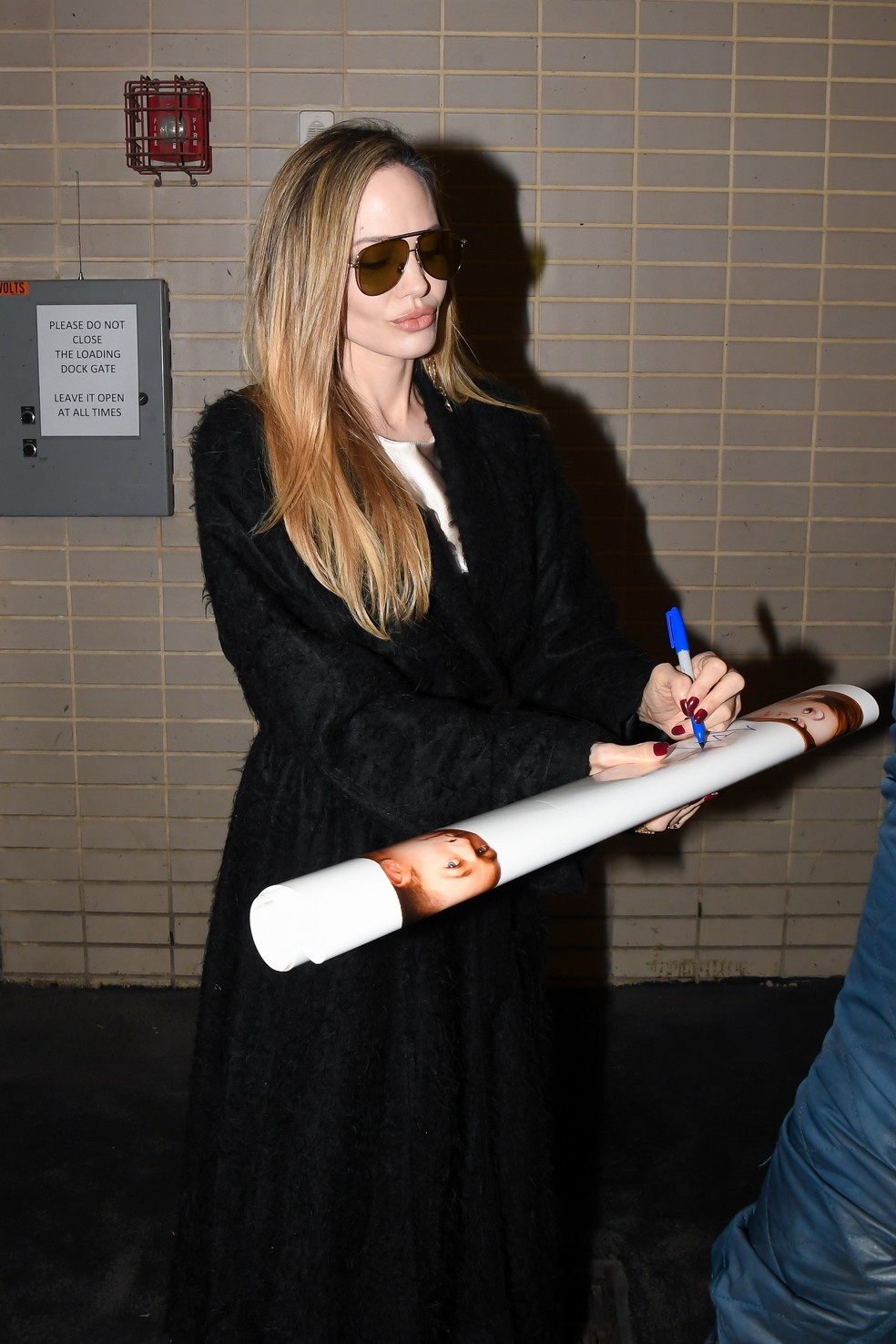 Angelina Jolie autografa pôster de fã que tem imagem do ex-marido Brad Pitt — Foto: Getty Images