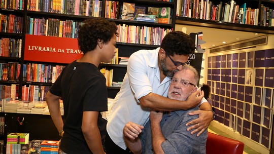 Luiz Fernando Guimarães ganha carinho do marido e dos filhos em lançamento de livro