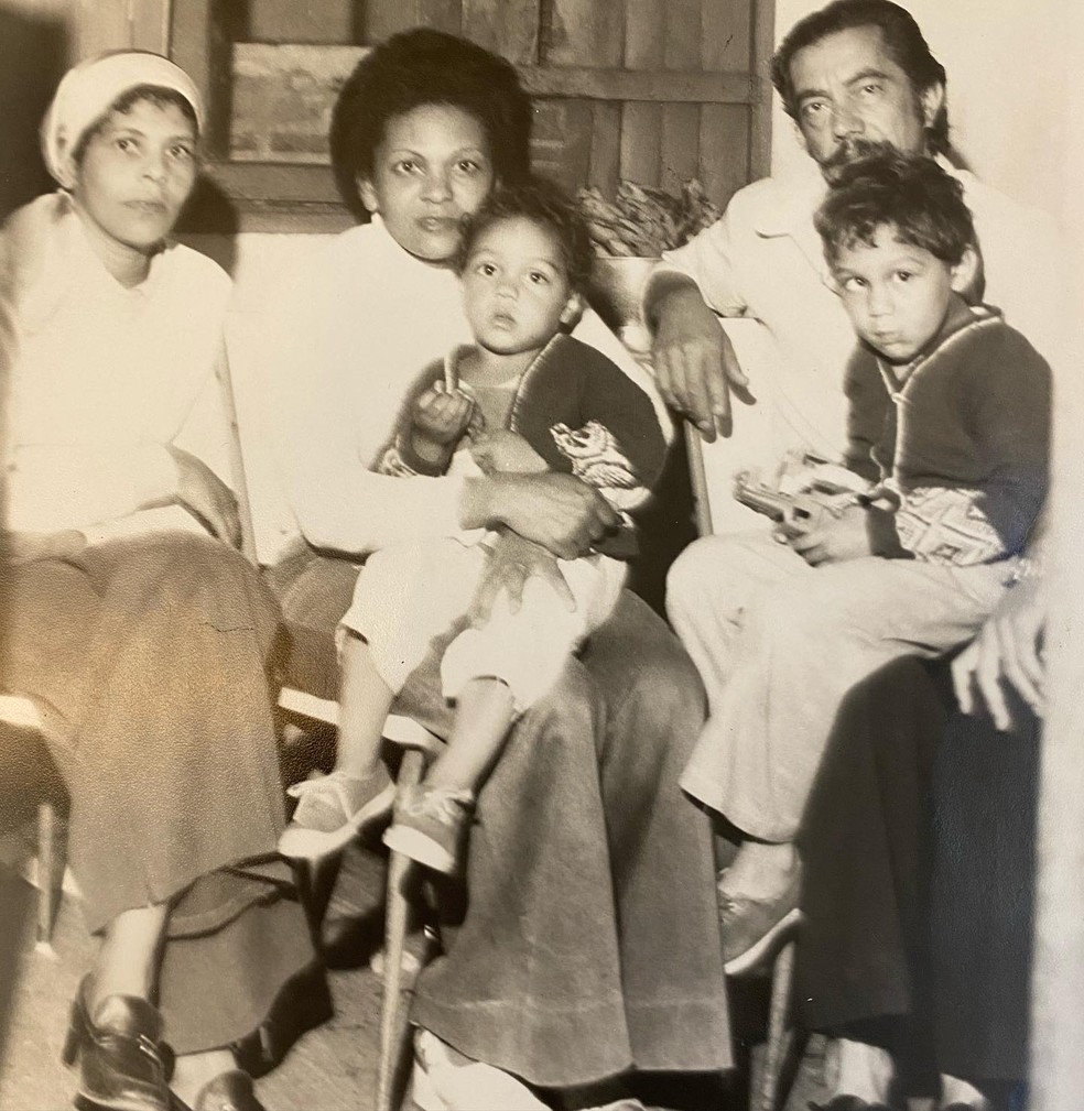 O cantor Belo no colo de sua mãe quando criança; seu pai está à direita — Foto: Reprodução/Instagram