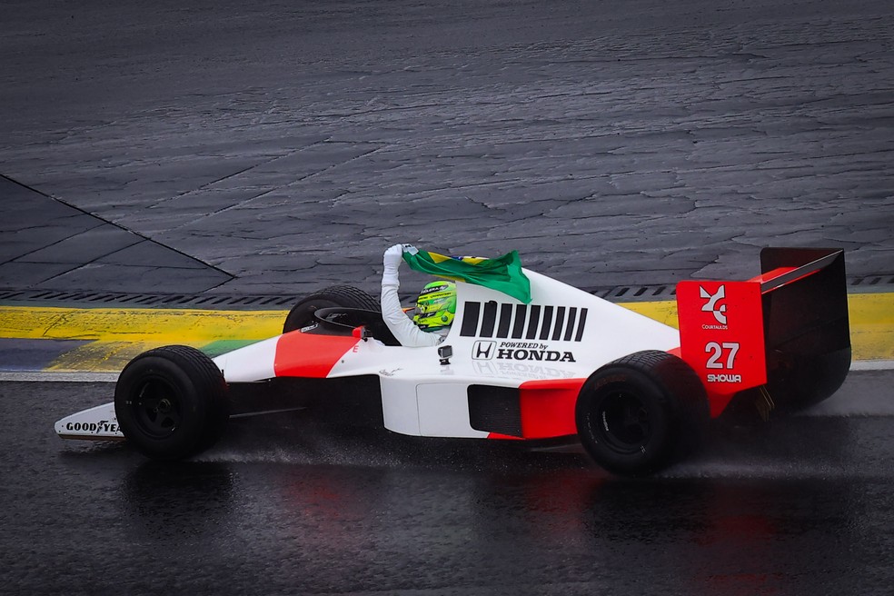 Lewis Hamilton exibe bandeira do Brasil ao dar volta com carro de Ayrton Senna durante tributo no GP de Sp — Foto: Manu Scarpa/Brazil News