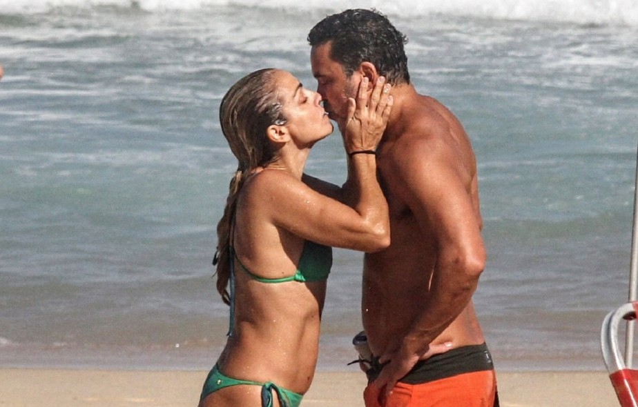 Ana Paula Guimarães, a ex-paquita Catuxa, troca beijos com marido em dia de praia