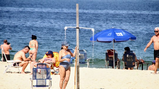 De boné e maiô, Betty Faria toma ducha em praia no Rio