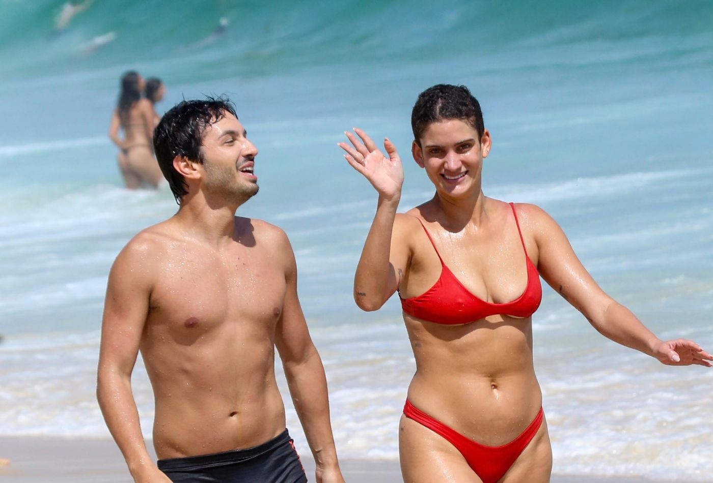 De biquíni vermelho, Laura Fernandez aproveita praia no Rio com amigo e dá 'tchauzinho' para paparazzo - Foto