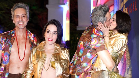 De saia e camisa aberta, Alexandre Nero dá beijão na mulher no Baile da Arara