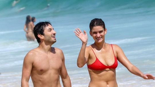 De biquíni vermelho, Laura Fernandez aproveita praia no Rio com amigo e dá 'tchauzinho' para paparazzo De biquíni vermelho, Laura Fernandez aproveita praia no Rio com amigo e dá 'tchauzinho' para paparazzo